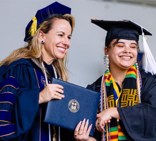 Kaitlynn Devitt (left) receives her degree at graduation. Devitt was awarded the Michele Kay Outstanding Journalist Award for her photojournalism work. 