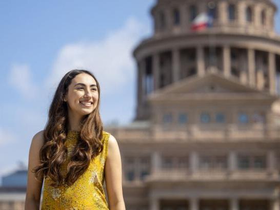 St. 爱德华的学生米歇尔·弗洛雷斯站在德克萨斯州国会大厦前, where she is interning.