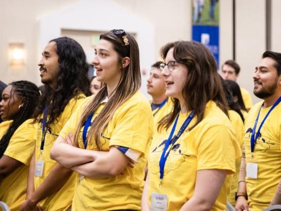 转移 students wear matching yellow shirts and participate in an orientation activity.