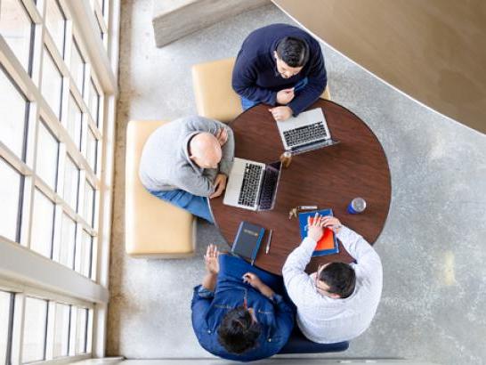 Students gather around a table to study in The Bill Munday School of Business.